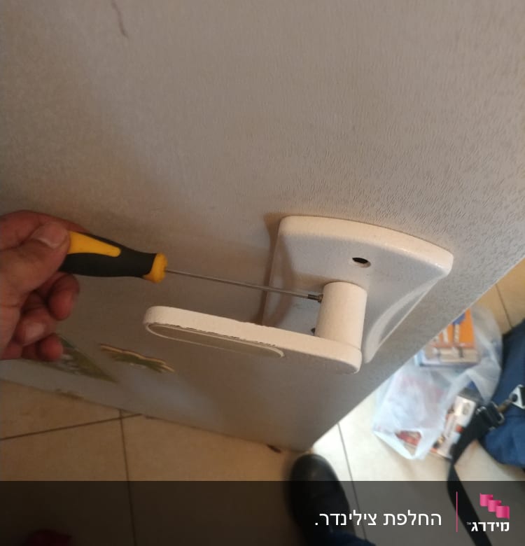 יד מחזיקה מברג ליד ידית דלת לבנה